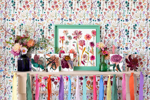 Floral greetings cards on a flowery shelf, in front of floral wallpaper. Rainbow floral bunting in the foreground.